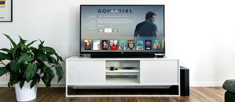 Wykorzystaj w pelni mozliwosci swojej soundbar dzieki standardom Vebos czarny telewizor z soundbarem na bialym meblu pod telewizorem, a po lewej stronie telewizora zielona roslina