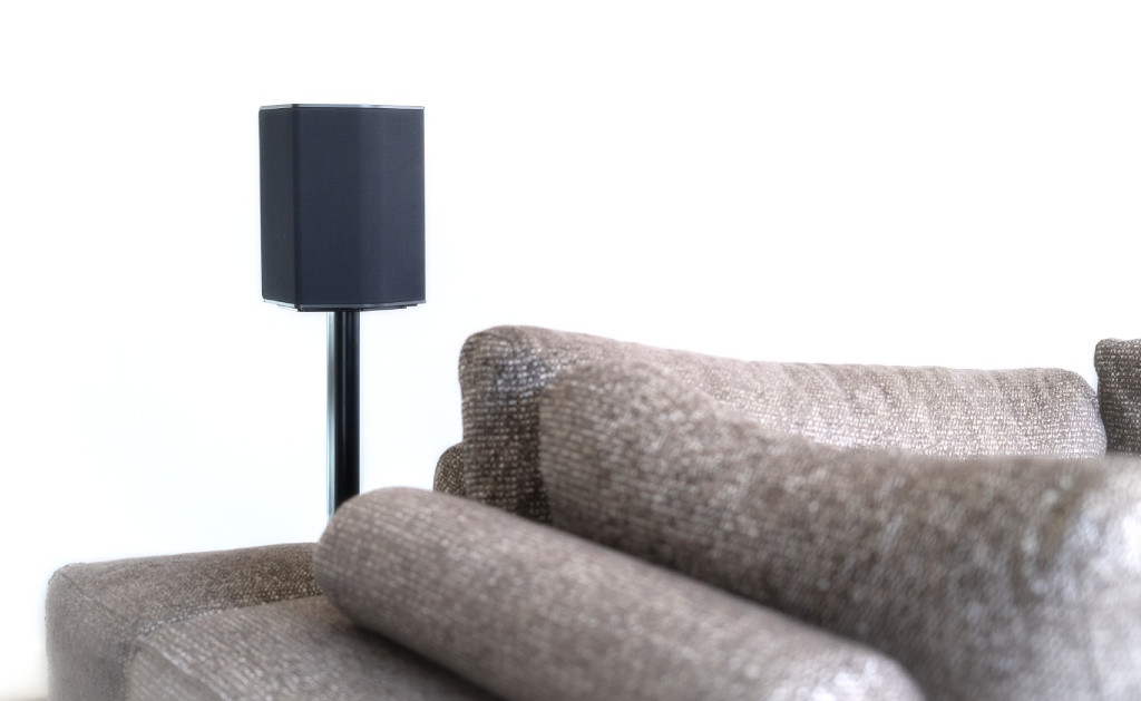 Glosnik multiroom na stojaku w salonie za sofa.
